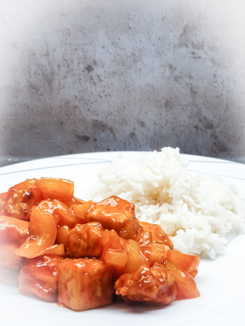 auf einem Teller angerichtet sind eine Portion Reis und der fertige süß-saure asiatische Tofu