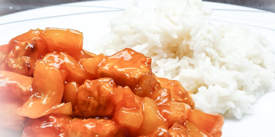 auf einem Teller angerichtet sind eine Portion Reis und der fertige süß-saure asiatische Tofu