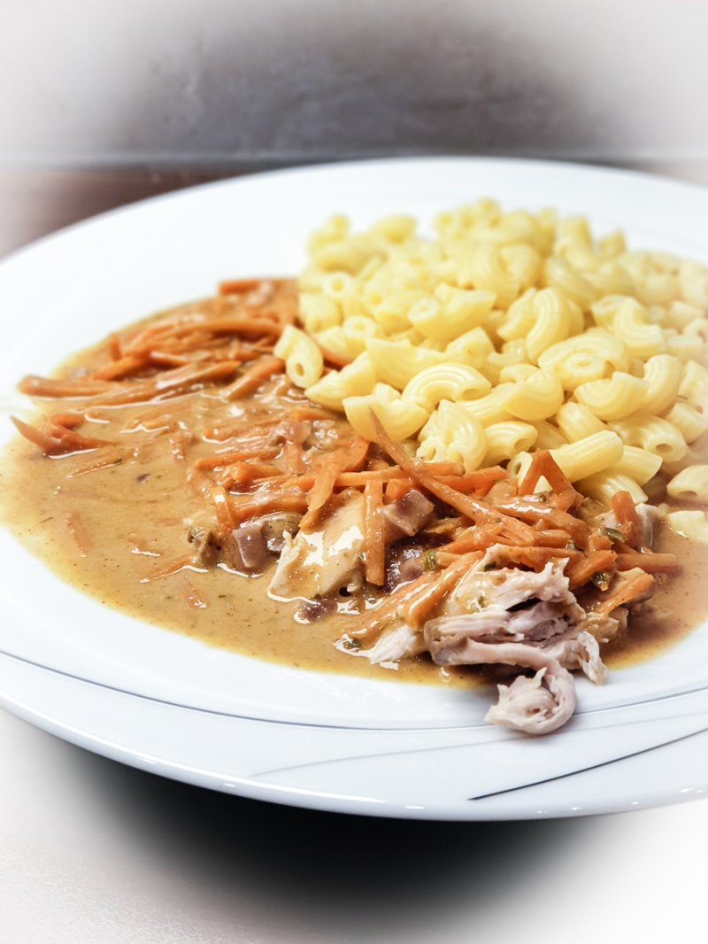 angerichteter teller hörnchennudeln mit karotten-hühnerfleisch-sauce