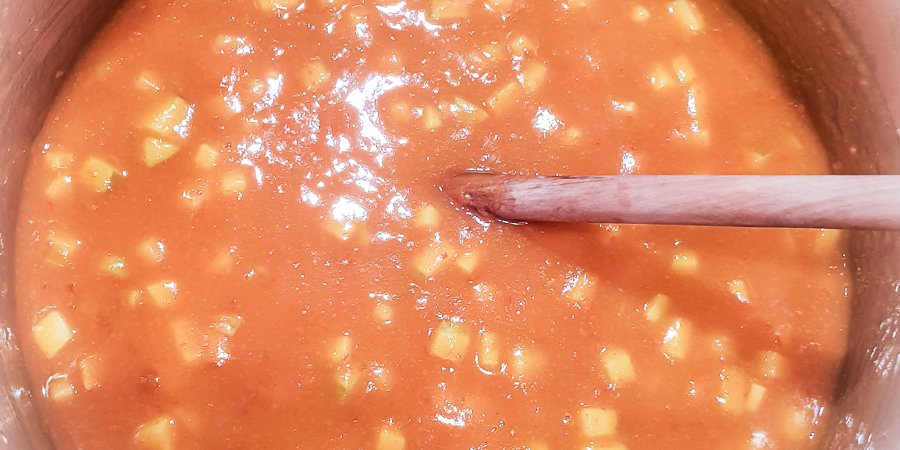 kürbis-apfel-marmelade wird im topf mit dem holzlöffel umgerührt