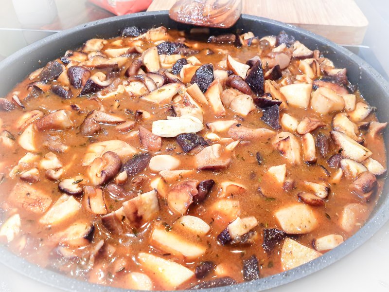 schwammerlgulasch in der pfanne wird mit dem holzlöffel umgerührt