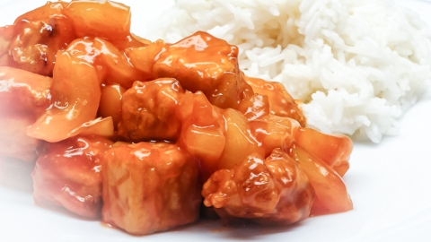 Tofu süß-sauer mit Reis auf einem Teller angerichtet sind eine Portion Reis und der fertige süß-saure asiatische Tofu