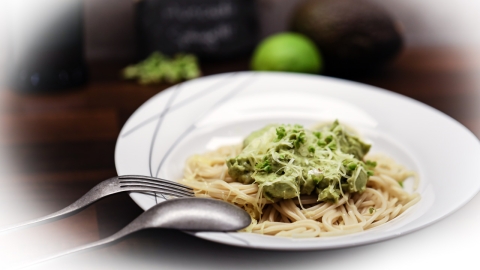 Avocado-Basilikum-Creme auf Spaghetti fertig angerichtete Portion der Avocado-Basilikum-Limetten-Nudeln mit Parmesan bestreut