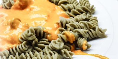 Rezept Tomatenfetasauce essfertig auf dem Teller sind grüne Spiralnudeln mit der Tomatenfetasauße