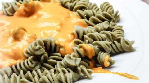 Rezept Tomatenfetasauce essfertig auf dem Teller sind grüne Spiralnudeln mit der Tomatenfetasauße