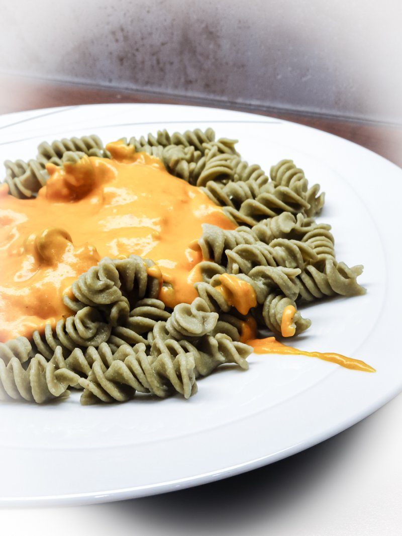 Rezept Tomatenfetasauce essfertig auf dem Teller sind grüne Spiralnudeln mit der Tomatenfetasauße